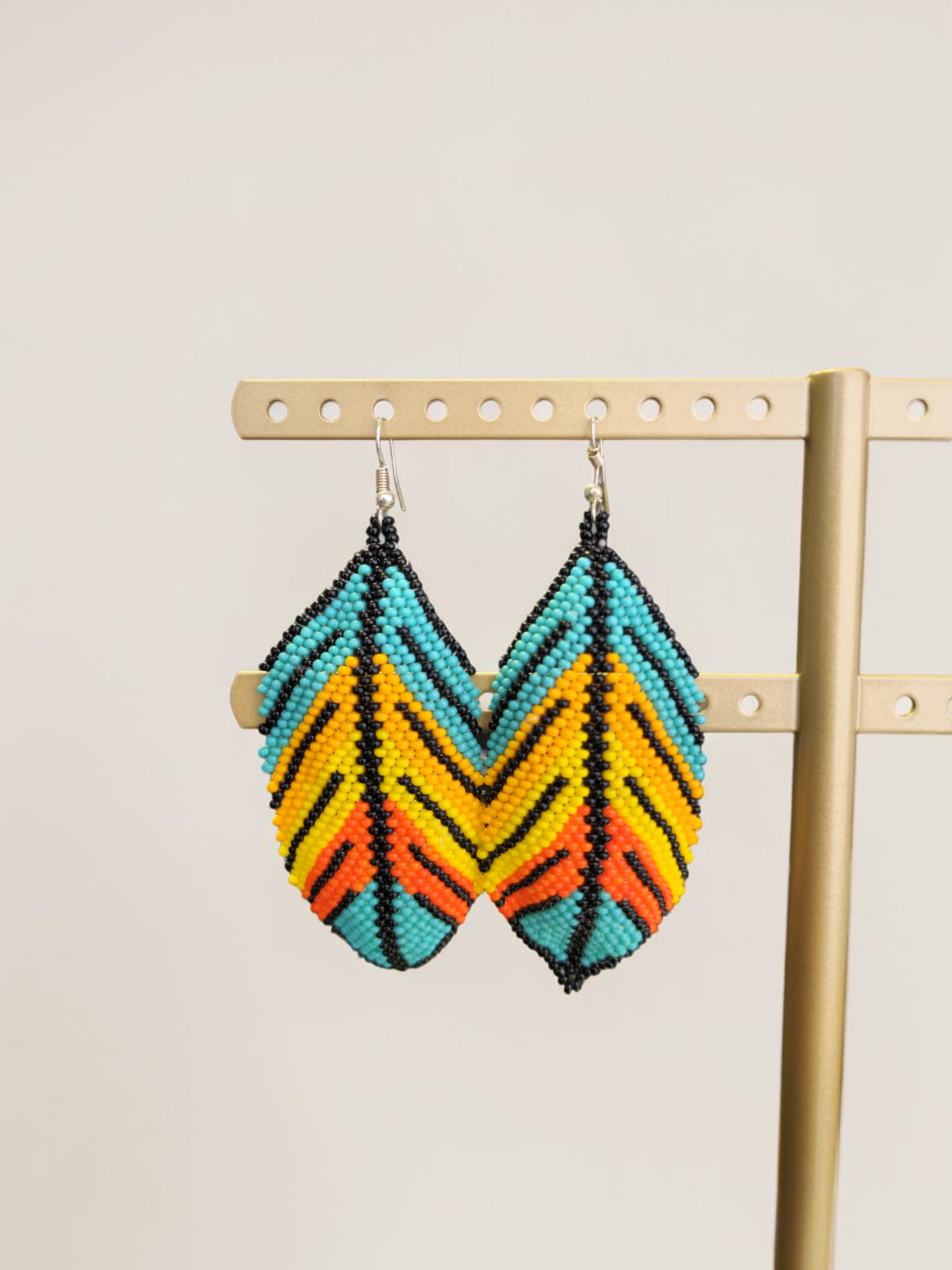 Colorful zigzag pattern earrings on a gold stand against a beige background