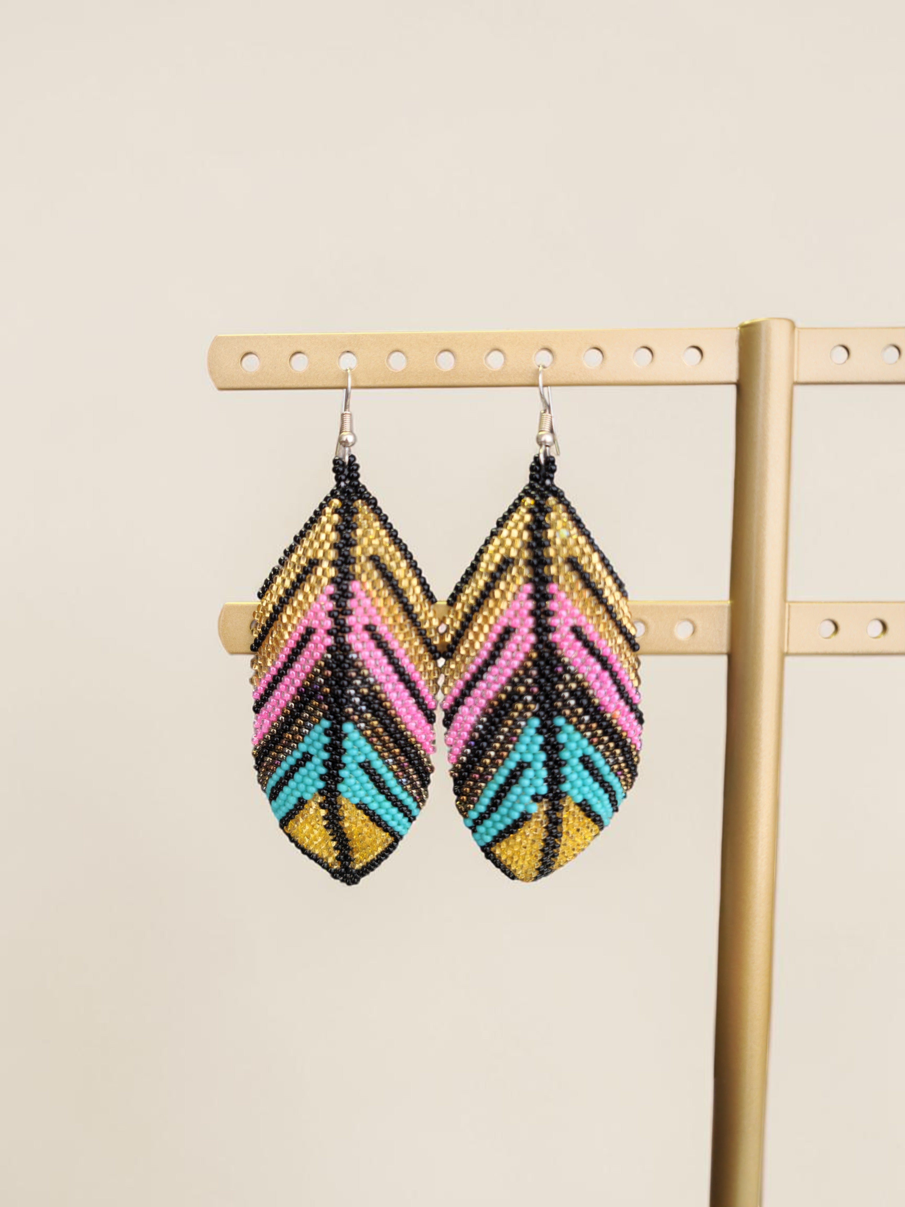 Pair of beaded earrings on a wooden stand against a beige background