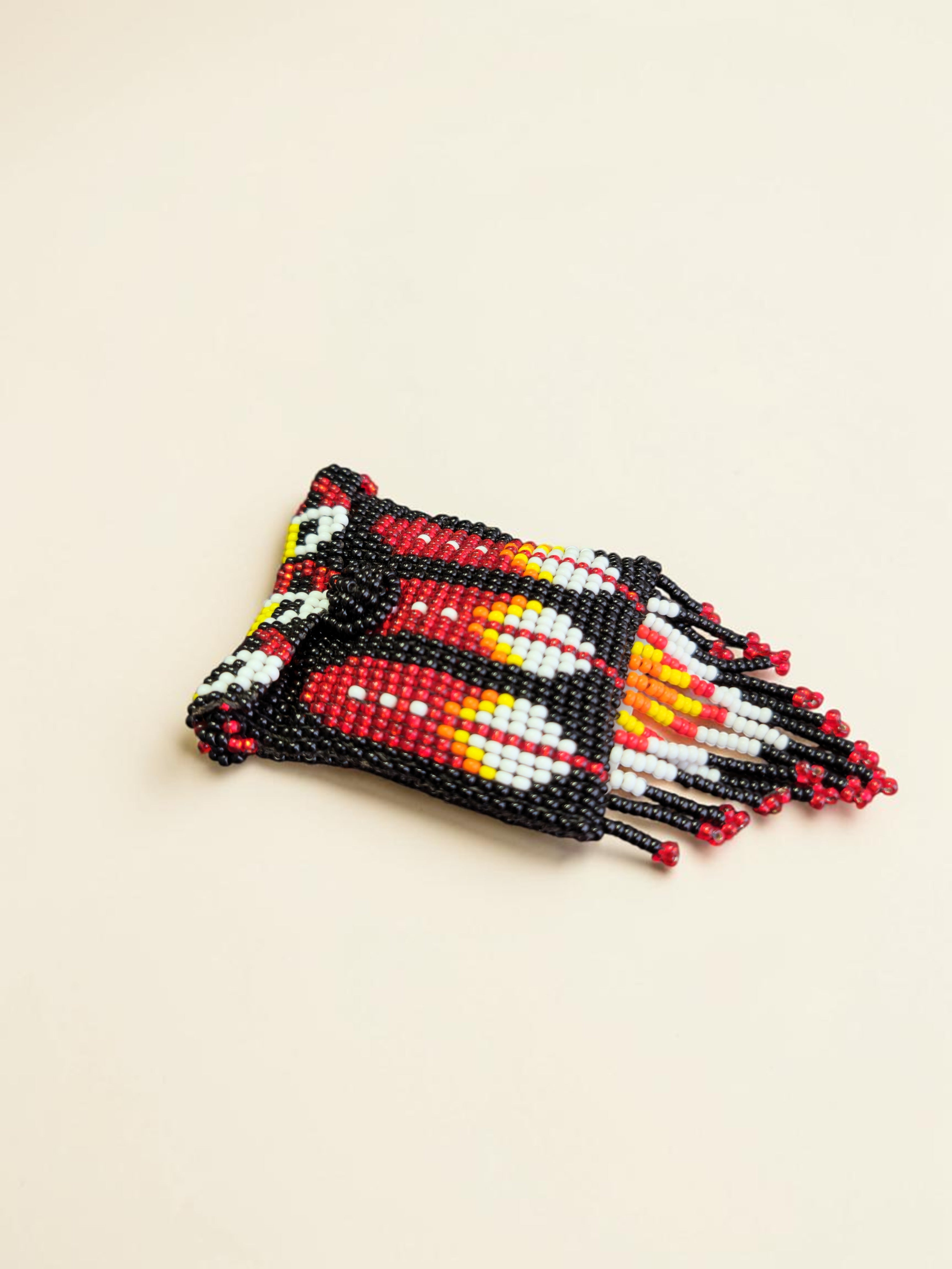 Beaded bracelet with red, black, and yellow pattern on a beige background