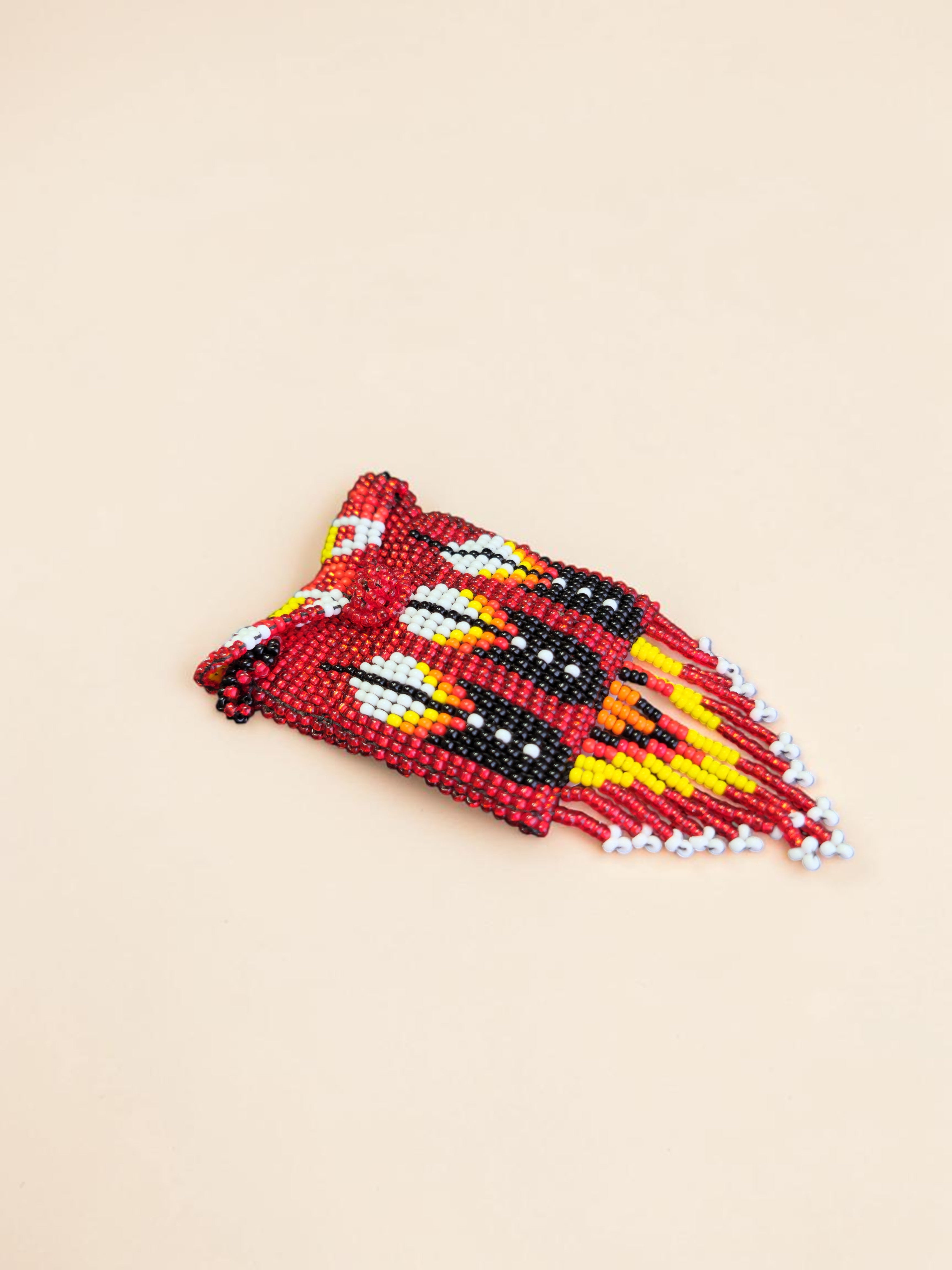 Beaded headband with red, yellow, and black pattern on a beige background