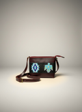 Brown leather crossbody bag with tribal design on a gray background
