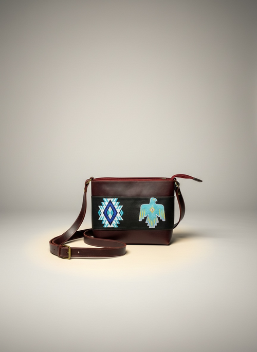 Brown leather crossbody bag with tribal design on a gray background